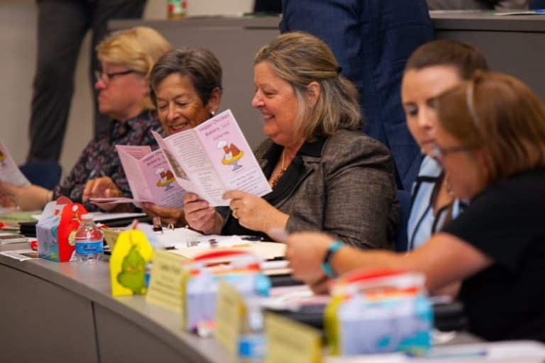 Carole Ratcliffe and judges looking at menus at AACC Pitch Competition